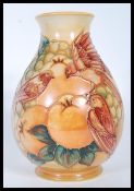 A Moorcroft pottery tube lined squat baluster vase, decorated with a birds amongst fruit,