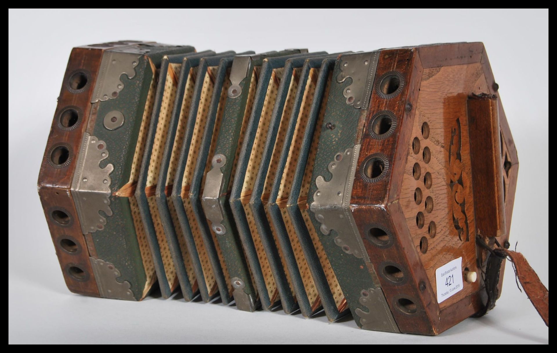 A vintage early 20th Century squeeze box of hexagonal form having pierced wood handles at each end