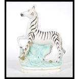 A 19th Century Victorian Staffordshire flatback figure of a zebra raised on a naturalistic plinth