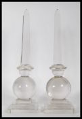 A pair of 20th Century glass obelisk centrepiece ornaments raised on square stepped bases with