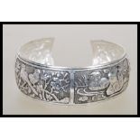 A Chinese silver bangle having panels of repousse decoration of animals including mandarin ducks,