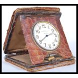 A vintage early 20th Century travelling desk clock having a white enamelled face with roman numerals