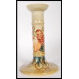 A Moorcroft pottery tube lined pedestal candlestick, decorated with a bird amongst fruit,