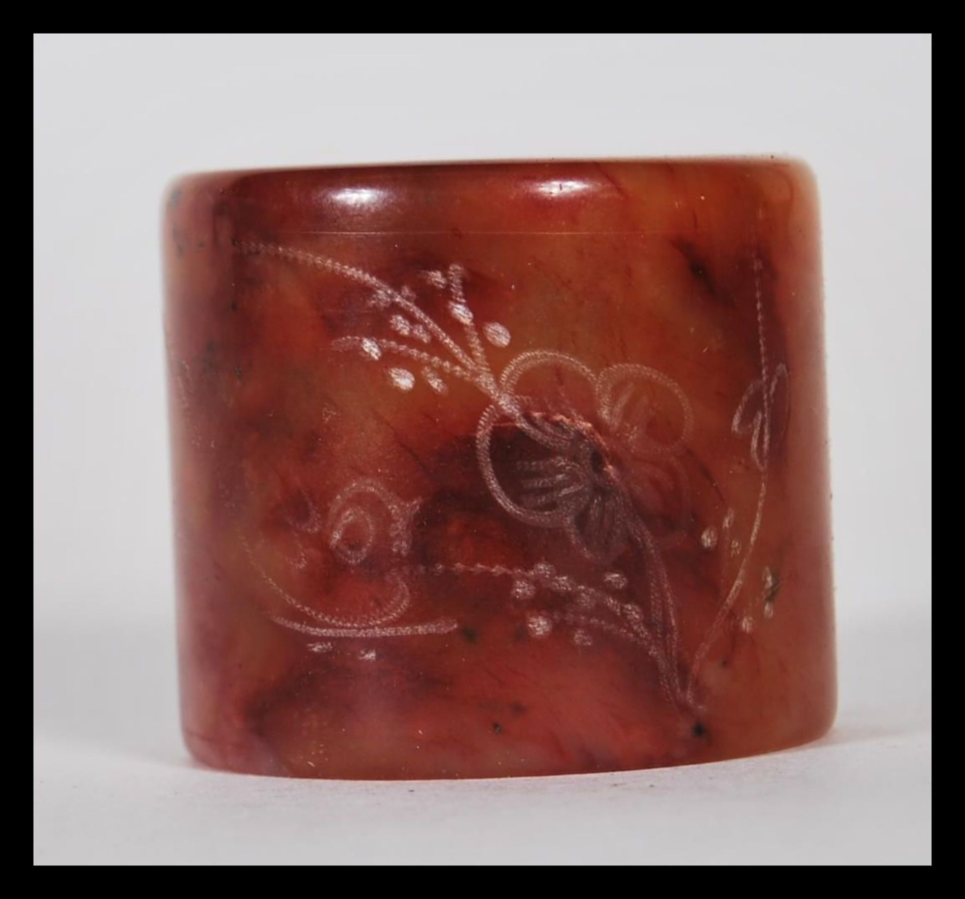 A early 20th Century Chinese large mottled dark red jade archer's thumb ring of cylindrical form.