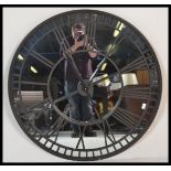 A large contemporary ebonised iron framed skeleton wall clock, mirrored backed and iron roman