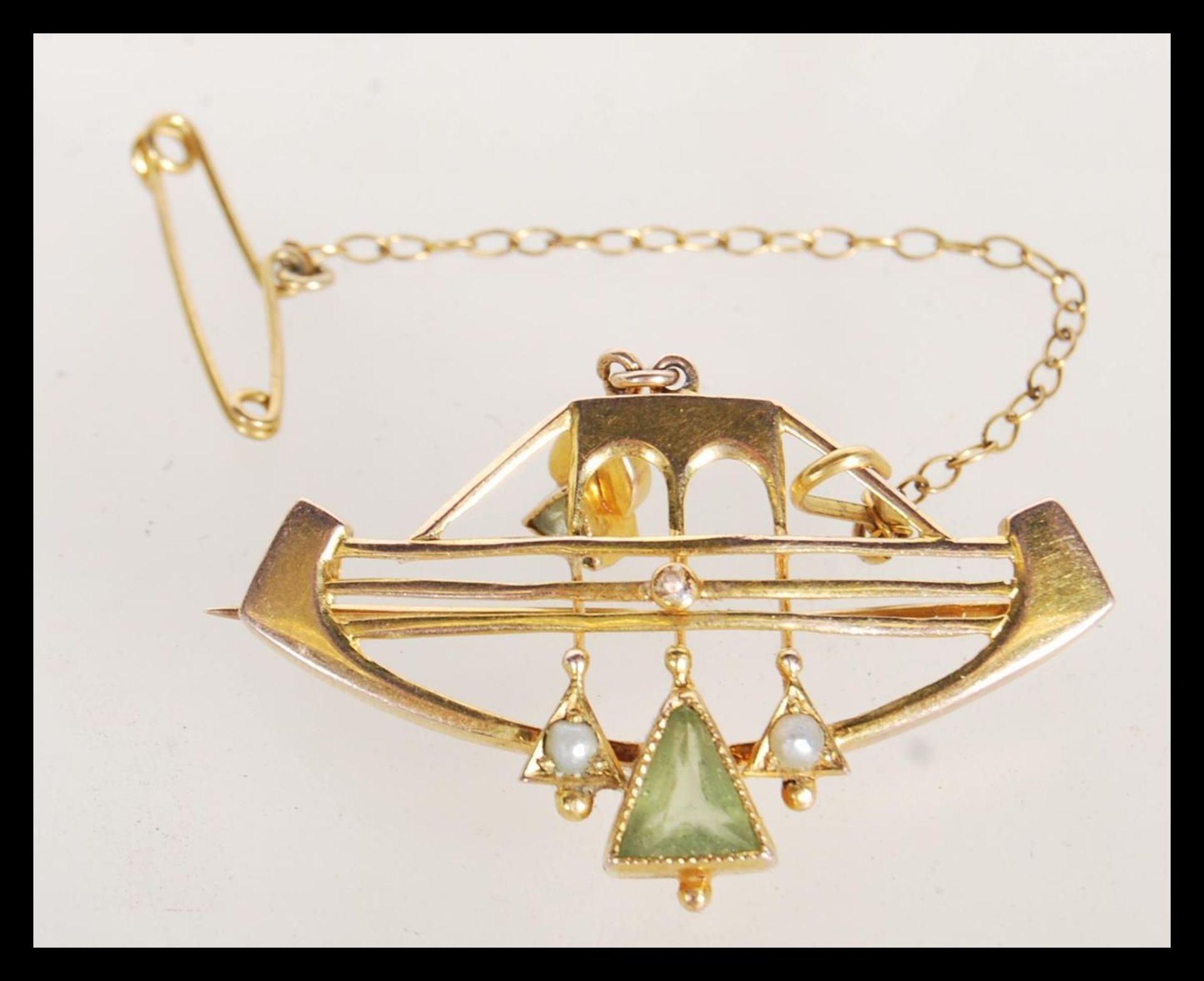 An early 20th Century stamped 9ct gold brooch being set with two triangular cut peridot and seed