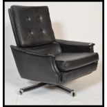 A retro 20th century 1960's black swivel recliner armchair with built in footstool /rest. Button