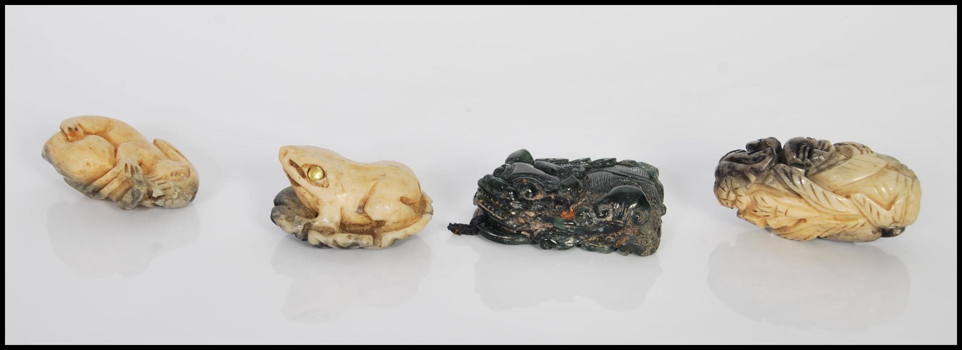 A group of four 20th Century Chinese carved toggles to include a green stone fu dog, a frog having