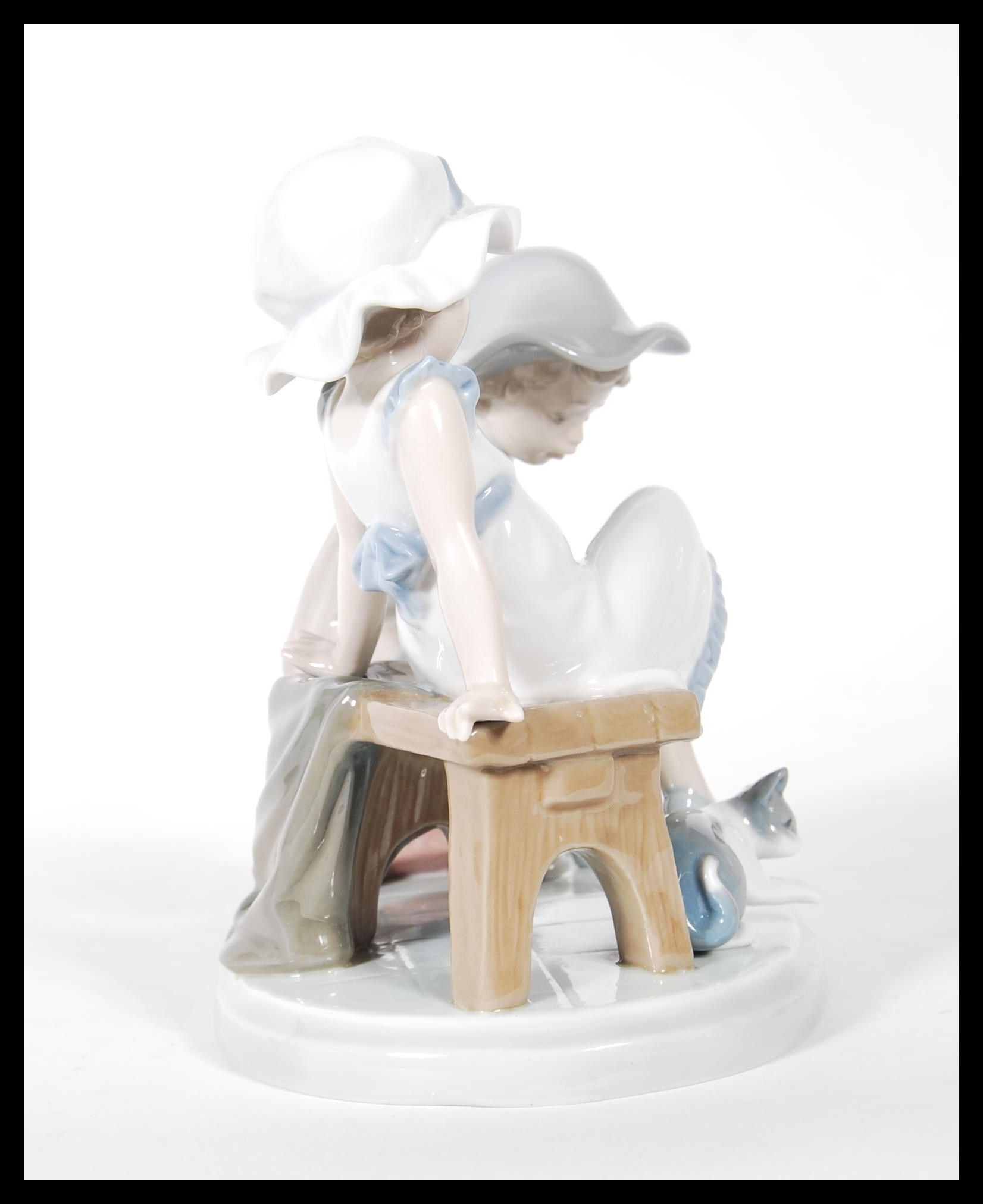 A Lladro ceramic figure group titled ' Try this One ', (5361) of a young girl trying on a shoe. - Image 2 of 6