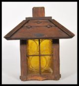An early 20th Century Arts and Crafts influenced wooden porch lantern, colored glass circular panels