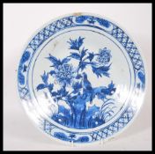 A 19th Century blue and white charger plate, depicting a bird perched on a branch with blue floral