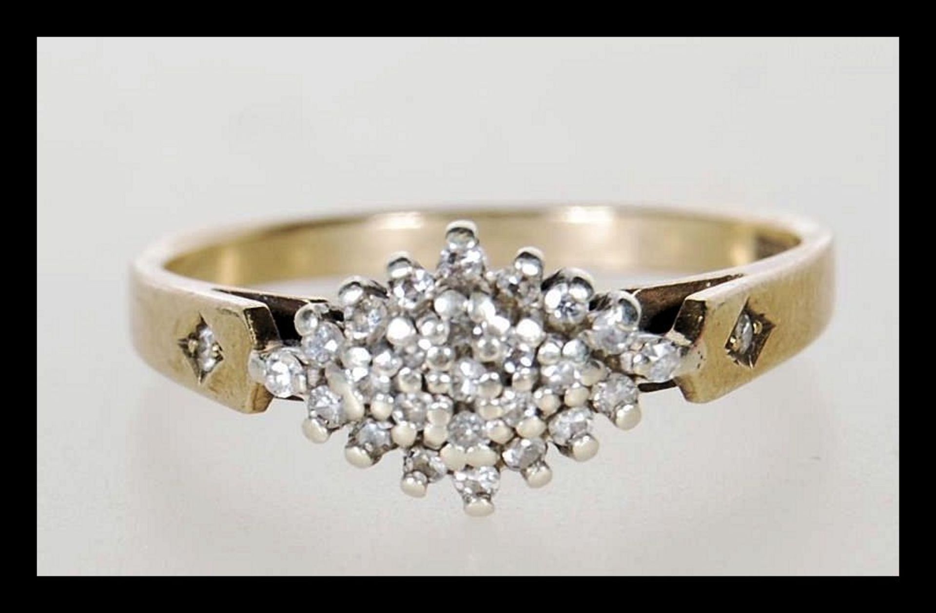 A hallmarked 9ct gold cluster ring set with white stones in a geometric cluster with accent stones