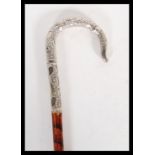 A silver white metal topped walking stick cane, having decorative crook handle with floral and