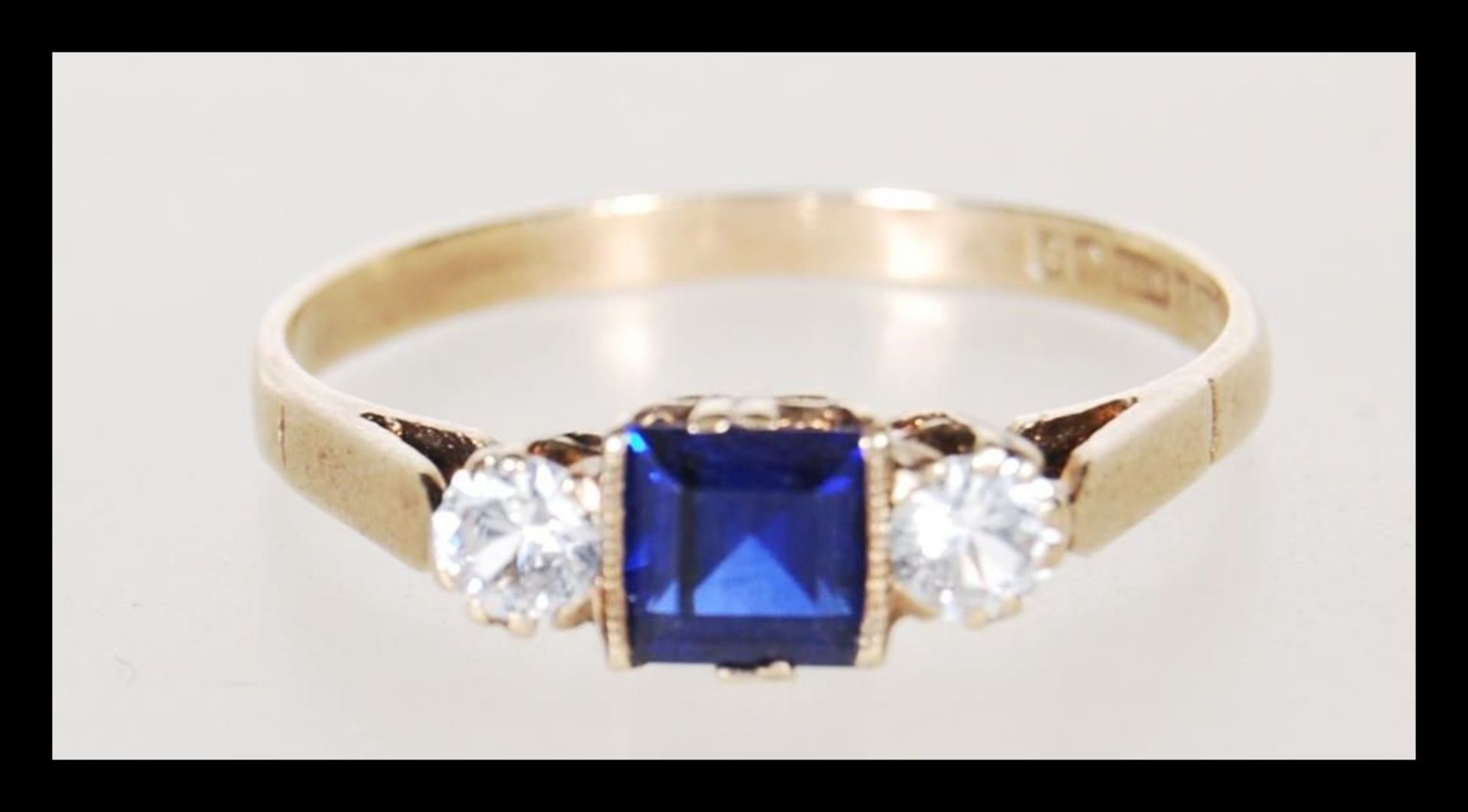 A hallmarked 9ct gold ladies ring set with a square cut blue stone flanked by two round cut white