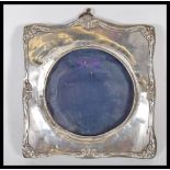 An early 20th Century silver hallmarked photo frame of square from having scrolled decoration