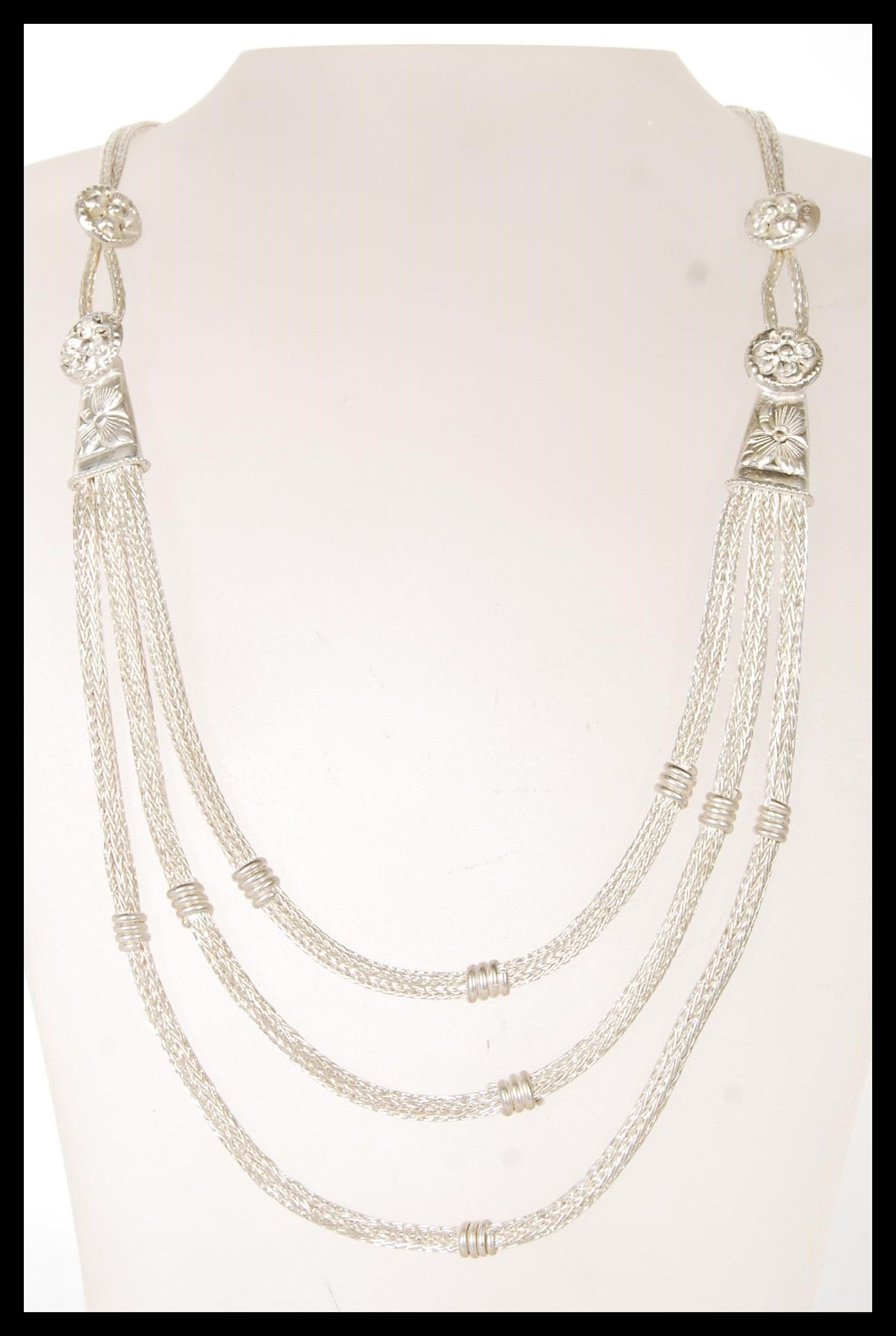 A 20th Century silver ethnic style necklace having three graduating snake chains with floral