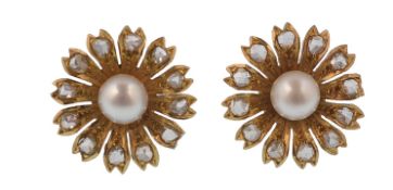 A pair of gold pearl and diamond earrings. The ear