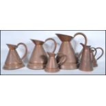 A collection of 6 19th century graduating copper cider measures. Each of shaped form having looped
