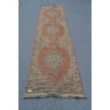 A large early 20th century handwoven Persian - Islamic runner rug having ochre faded red ground with