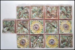 A collection of 13 20th century terracotta  majolica painted pottery tiles cast in relief with