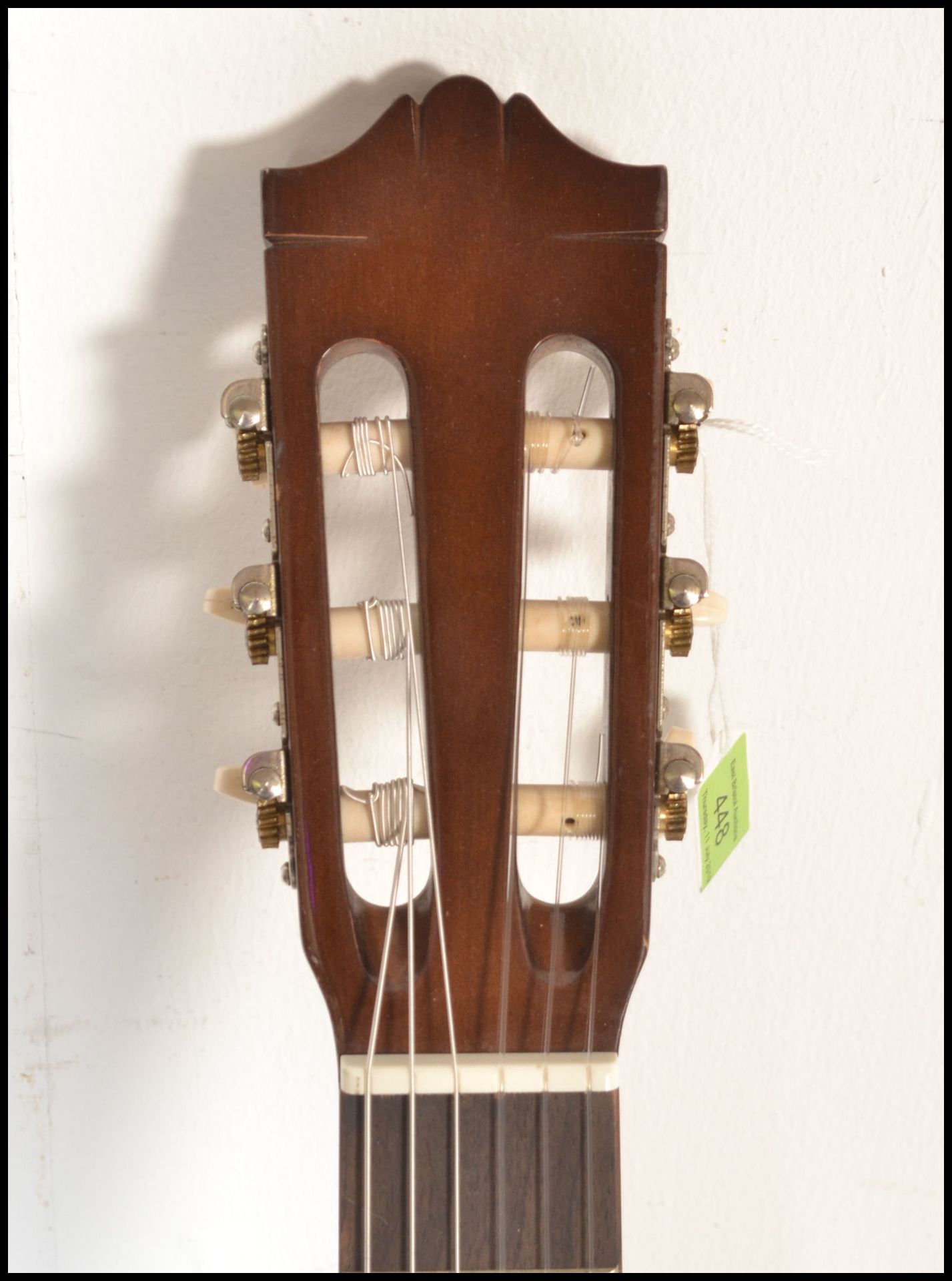 A Yamaha C40 six string acoustic guitar having a shaped hollow body with white tuning pegs and paper