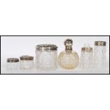 A group of early 20th Century silver topped and cut glass bodied dressing table pots, most having
