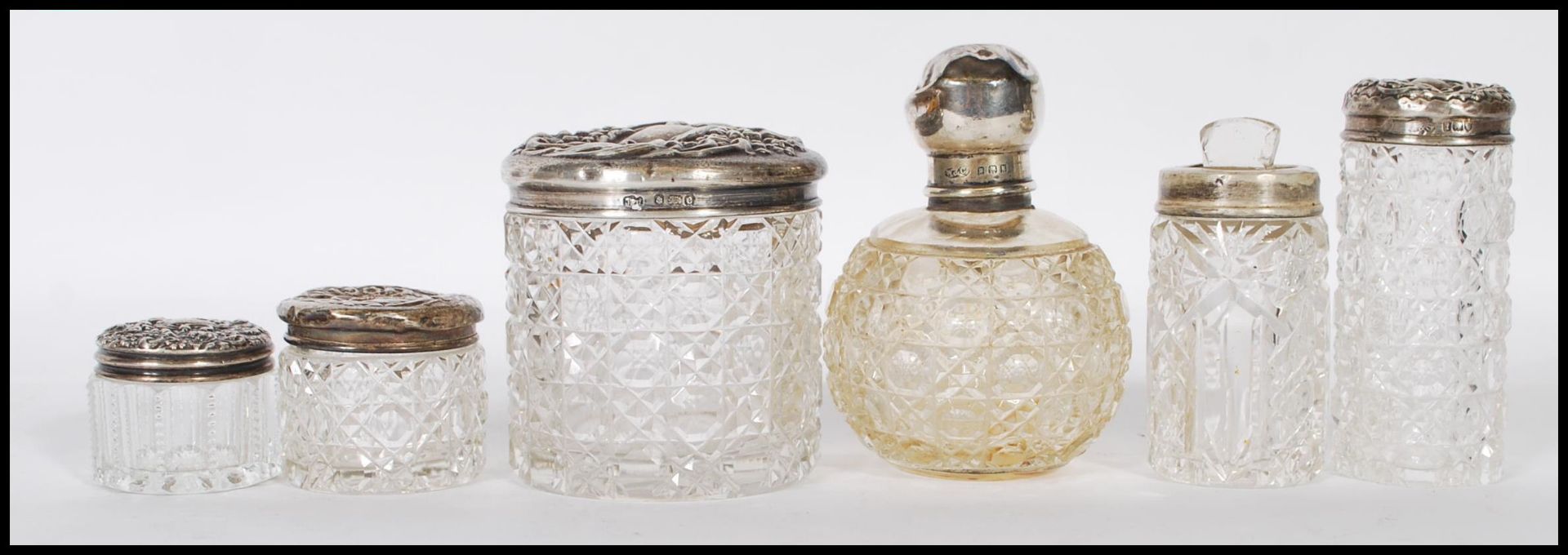 A group of early 20th Century silver topped and cut glass bodied dressing table pots, most having