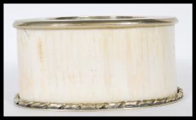 An early 20th Century ivory wine coaster / stand having a  white metal twist design base and top.