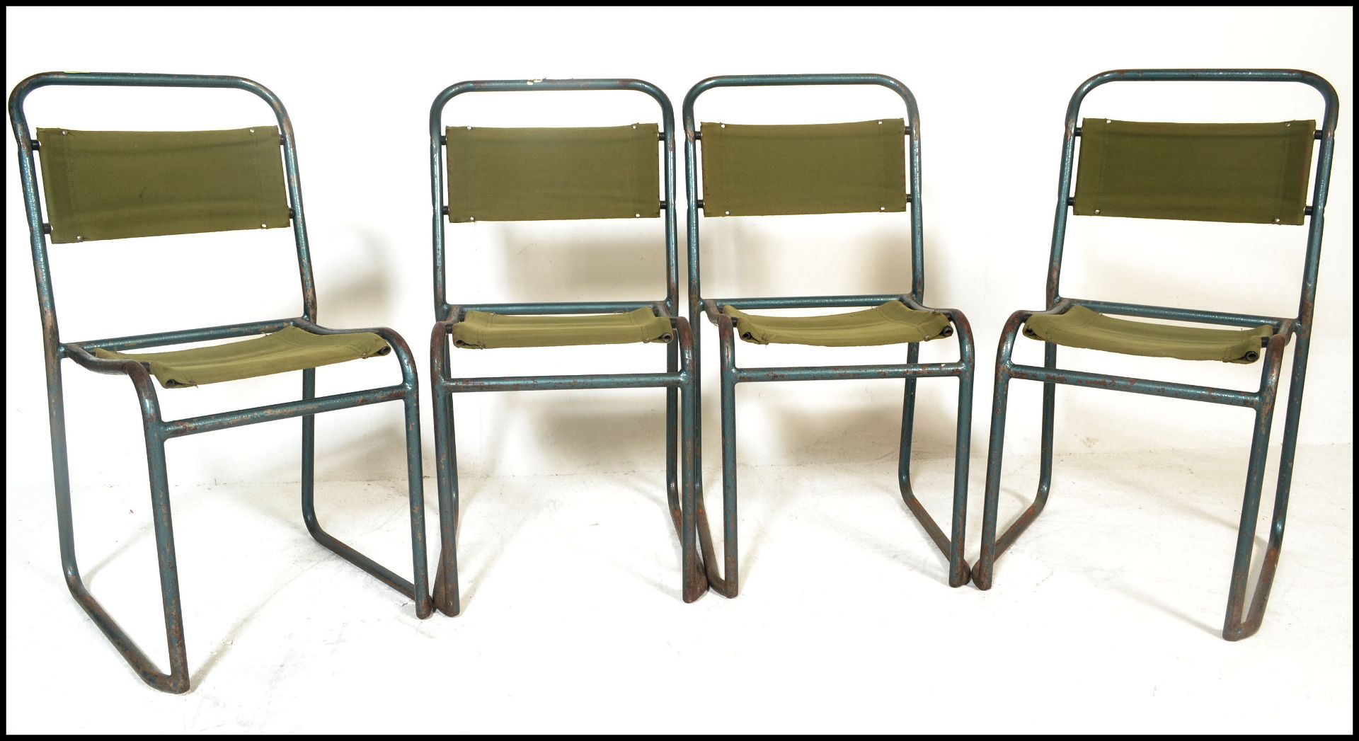 A set of four vintage mid 20th Century metal tubular stacking chairs, original canvas seat pads