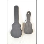 Two black faux leather guitar cases one having red velvet interior and lock catches, together with