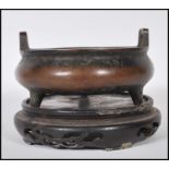 A 19th Century Chinese bronze censer ding bowl raised on tripod stubb feet with hoop handles and six