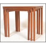 A retro 20th Century teak wood Danish nest of three graduating occasional tables raised on  turned