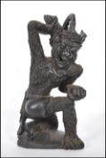 A 20th Century carved wooden figure in the form of Hauman the monkey God, being knelt on one knee
