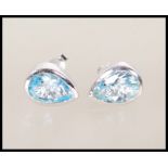 A pair of silver and blue topaz stud earrings each with post backs. The blue topaz in pear drop