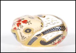 A crown Derby paperweight in the form of a mouse in a curled position with red and yellow floral