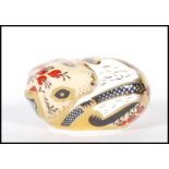 A crown Derby paperweight in the form of a mouse in a curled position with red and yellow floral