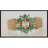 A hallmarked 9ct gold cluster ring having a central illusion set diamond with a halo of emeralds