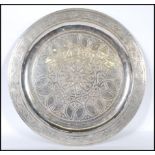 An early 20th Century Anglo Persian silver white metal wall charger having a chase design border