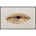 A 9ct gold vintage boat shaped brooch having pierced foliate decoration, set with a central garnet
