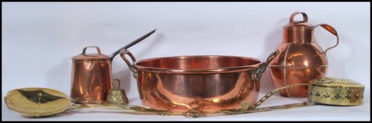 A collection of copper and brass wares dating from the 19th Century to include a large preserve pan,