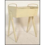A vintage retro wooden sewing box being painted in white with angular tapering legs and brass