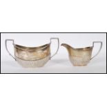 A near matching silver hallmarked sugar bowl and creamer set. The twin handled sugar bowl with