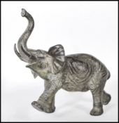 A large believed early 20th century bronze figural scuplture of an African Elephant with raised