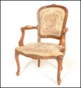 A 20th Century French carved fruitwood fauteuil or open arm elbow chair, the seat and back