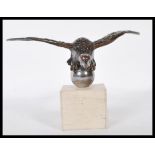A vintage 20th Century car mascot in the form of a vulture with spread wings mounted on an orb above