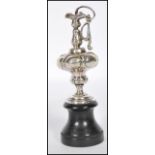 A silver hallmarked miniature amphora / ewer cast in relief and raised on a wooden ebonised socle