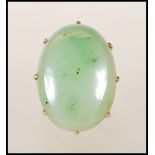 A ladies 9ct gold dress ring set with a large oval green nephrite cabochon. Unmarked but tests as