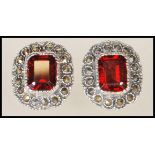 A pair of ladies Renaissance style earrings. Each with cushion cut red stones with a halo surround