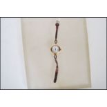 A early 20th Century hallmarked 9ct gold ladies wrist watch having a white enamel face with gilt