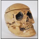 A 20th Century novelty chalk ware tobacco jar in the form of a skull, the lid being the coronal